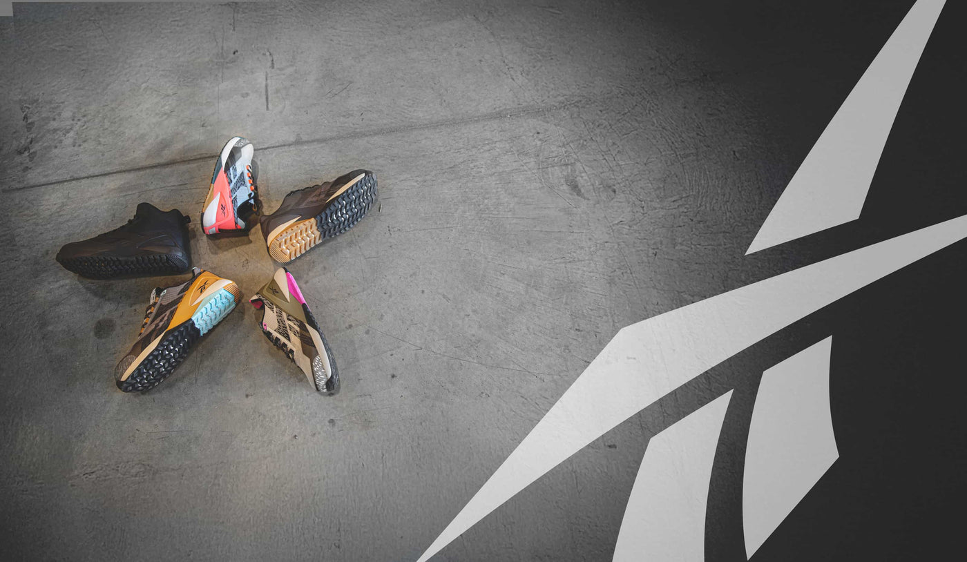 Reebok athletic work shoes and boots displayed on a warehouse floor with the Reebok logo overhead.