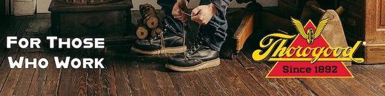 Person lacing up black Thorogood work boots on wooden floor with Thorogood logo and 'For Those Who Work' text
