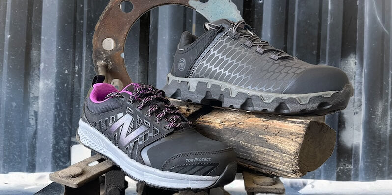 Black steel toe safety shoes with purple and gray accents, set on an industrial backdrop