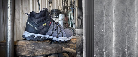 "Rugged steel-toe work shoe displayed on a rustic wooden surface in an industrial setting."