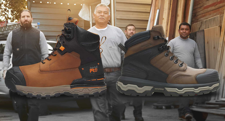 Two large work boots displayed in front of a group of people in an outdoor setting.